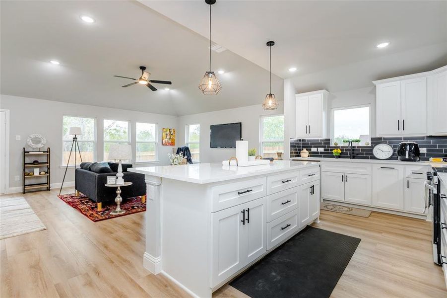 Kitchen with vaulted ceiling, a center island, plenty of natural light, and light hardwood / wood-style floors