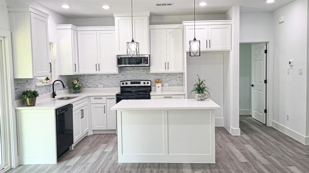 Kitchen featuring pendant lighting, light wood-type flooring, a center island, and appliances with stainless steel finishes