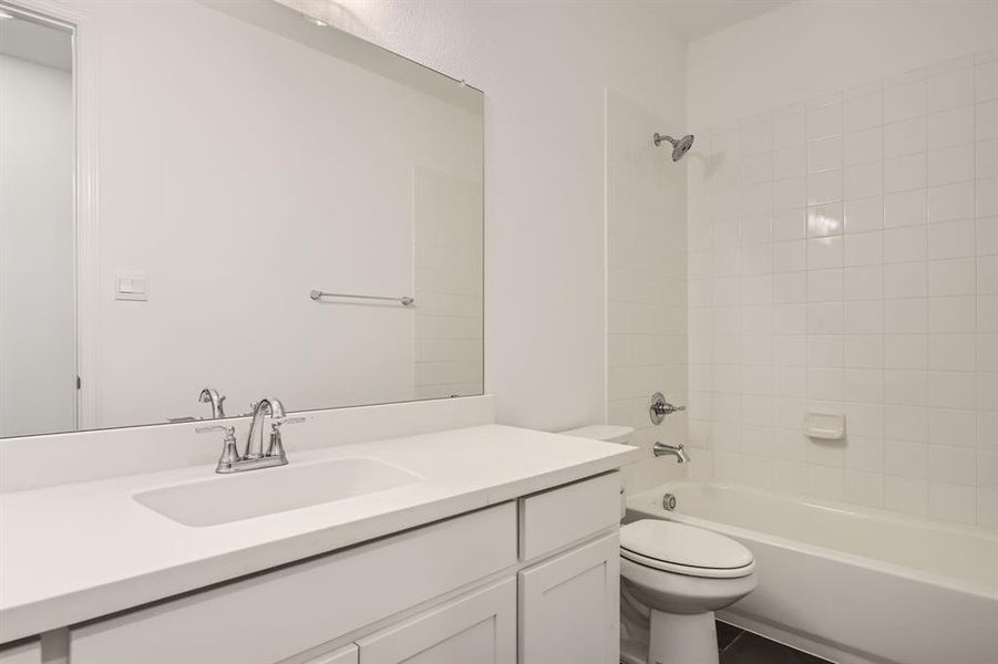 Full bathroom with vanity, tiled shower / bath combo, toilet, and tile patterned floors