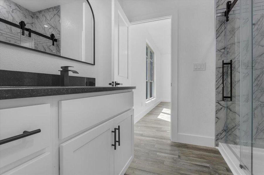 Bathroom with hardwood / wood-style floors, a shower with shower door, and vanity