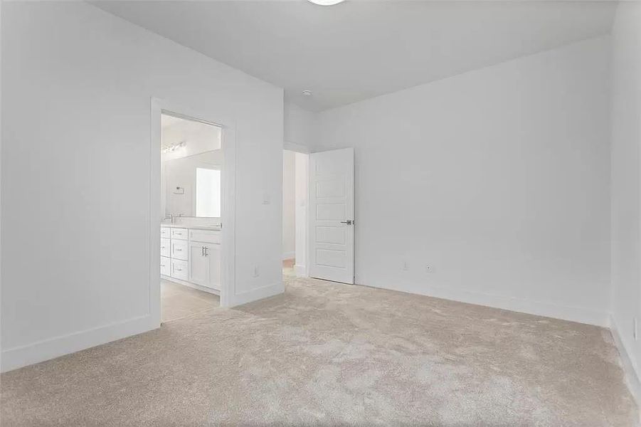 Unfurnished bedroom featuring connected bathroom and light colored carpet
