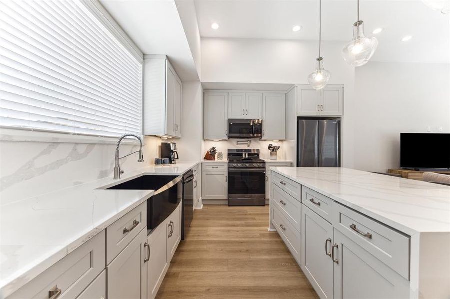 Gourmet kitchen with classic quartz counters and backsplash. Black toned stainless steel appliances are all included.