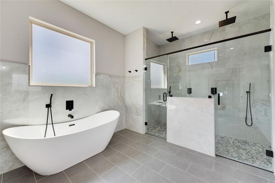 Bathroom featuring shower with separate bathtub, tile patterned flooring, and tile walls