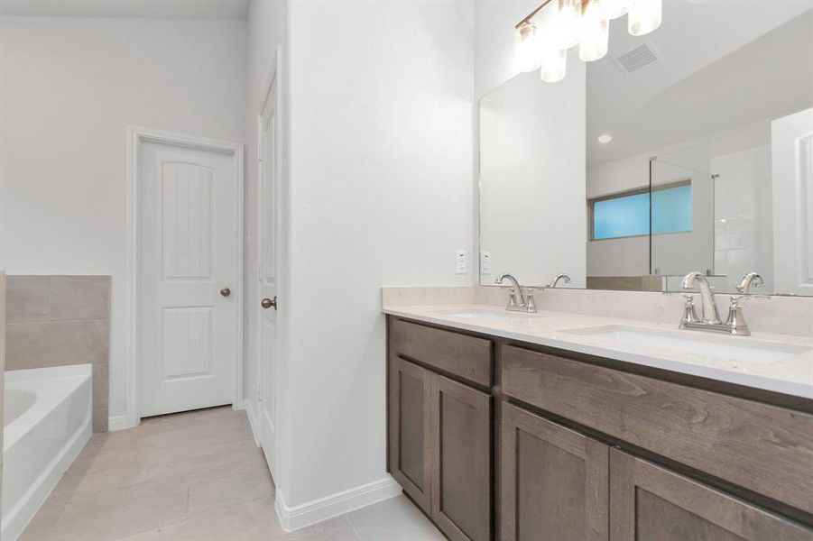 Another perspective of the primary bathroom showcases the expansive double vanity and modern design elements that cater to both aesthetics and practicality. The neutral tones and quality finishes create a soothing atmosphere. **This image is from another Saratoga Home - Clover floorplan.**