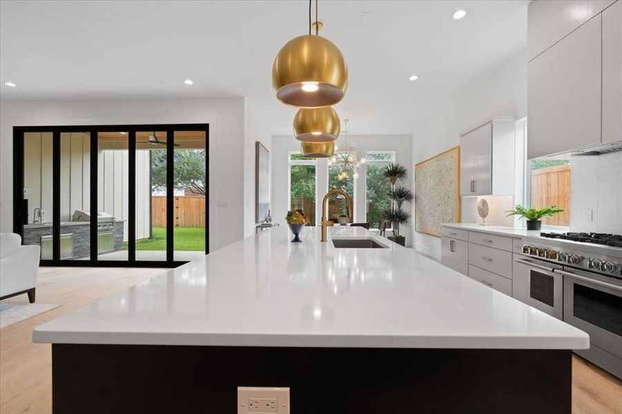 Kitchen with pendant lighting, double oven range, and a large island with sink