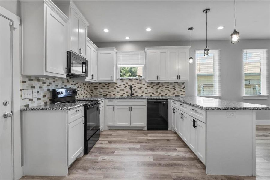 Kitchen with light hardwood / wood-style flooring, kitchen peninsula, black appliances, backsplash, and sink