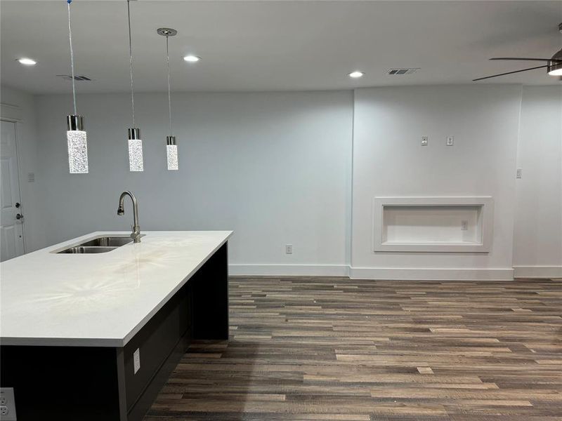 Kitchen featuring pendant lighting, an island with sink, dark wood-type flooring, sink, and ceiling fan