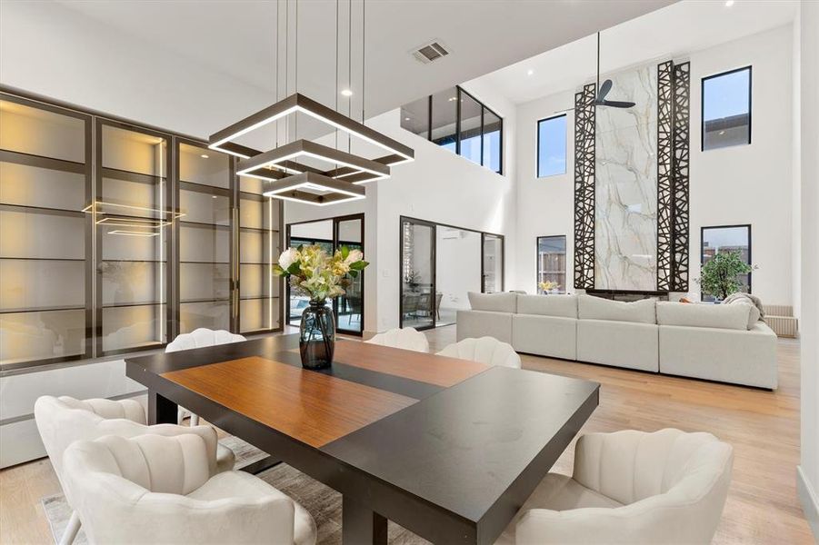 Dining space featuring light wood-type flooring and a towering ceiling