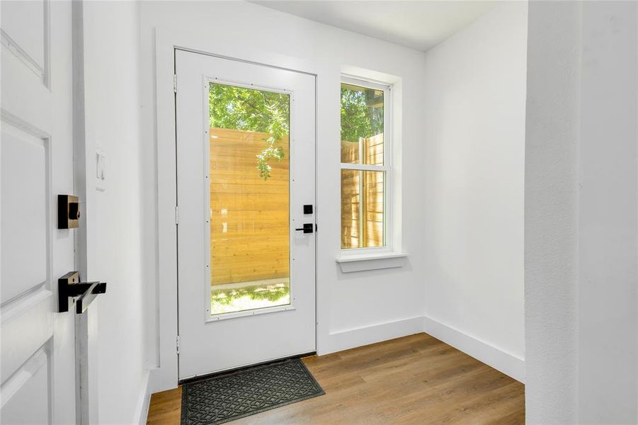 Doorway with a healthy amount of sunlight and light hardwood / wood-style flooring
