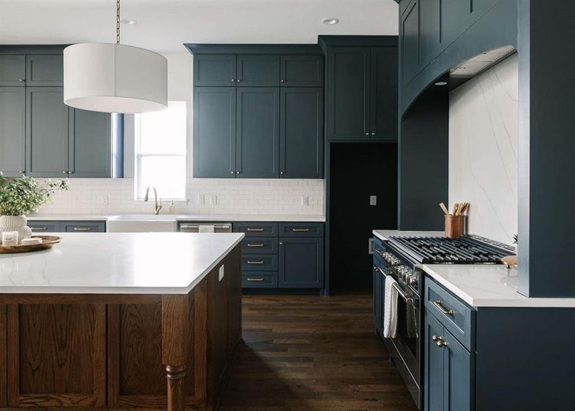 Kitchen featuring pendant lighting, dark wood-type flooring, sink, backsplash, and stainless steel range