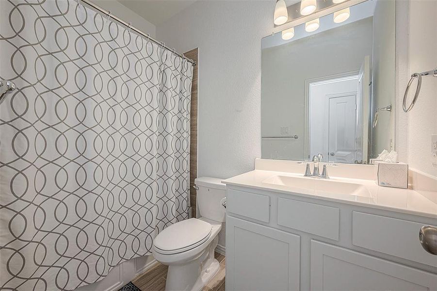 This bathroom features a toilet, sink, and mirror, providing the essentials in a clean and functional design.