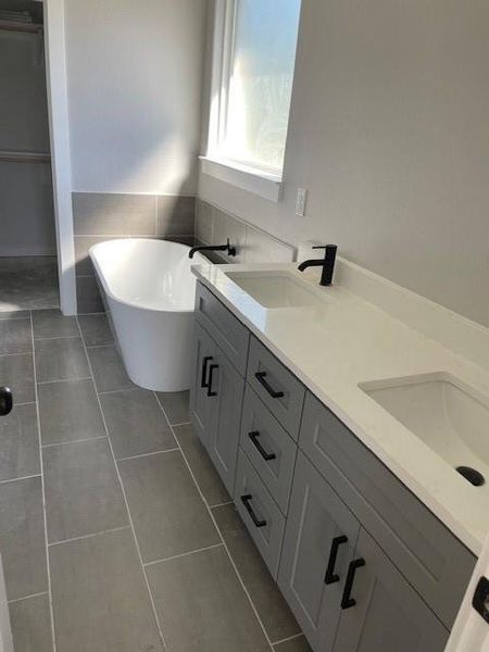 Bathroom with tile patterned flooring, a bathing tub, and vanity