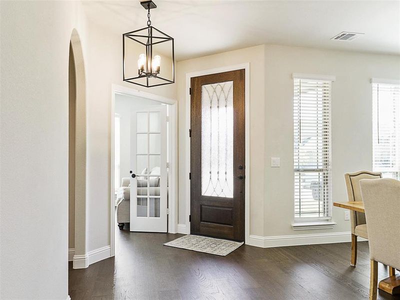 Foyer with dark wood-type flooring and a notable chandelier