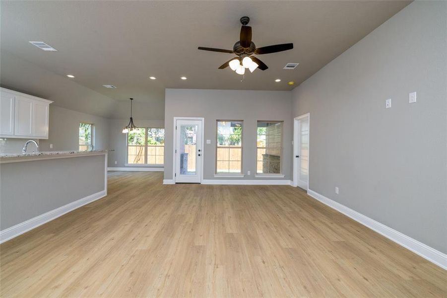 Unfurnished living room with sink, light wood-type flooring, and ceiling fan