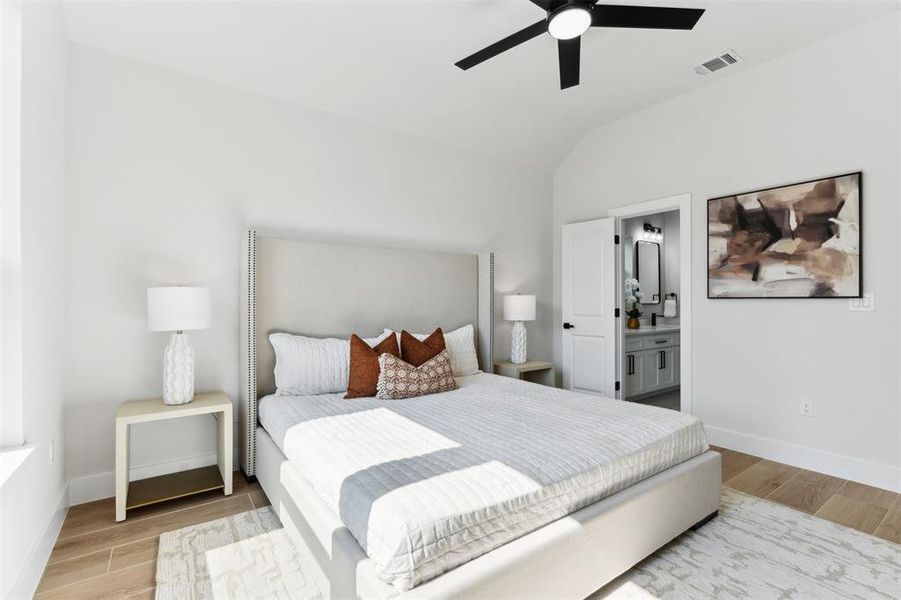 Bedroom featuring vaulted ceiling, ceiling fan, connected bathroom, and light hardwood / wood-style floors