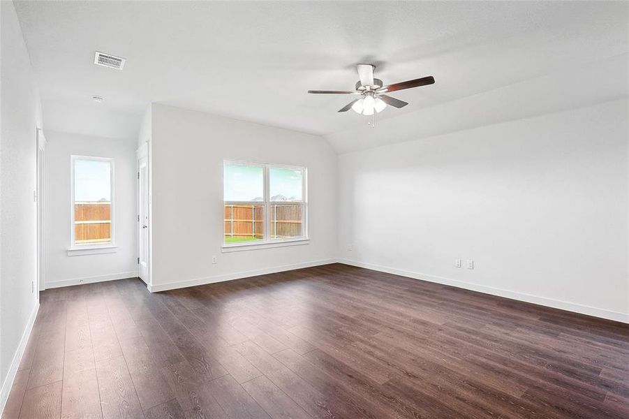 Empty room featuring dark wood-type flooring, ceiling fan, and vaulted ceiling