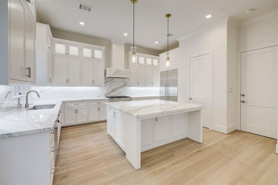 Double stacked white cabinetry is accented with glass front upper doors that are each beautifully lit to display your collectibles.