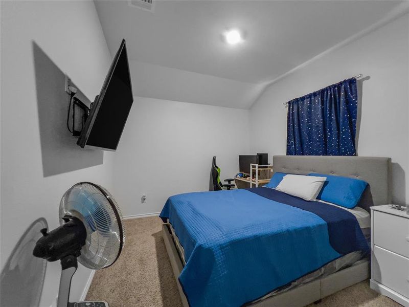 Bedroom featuring light carpet and lofted ceiling