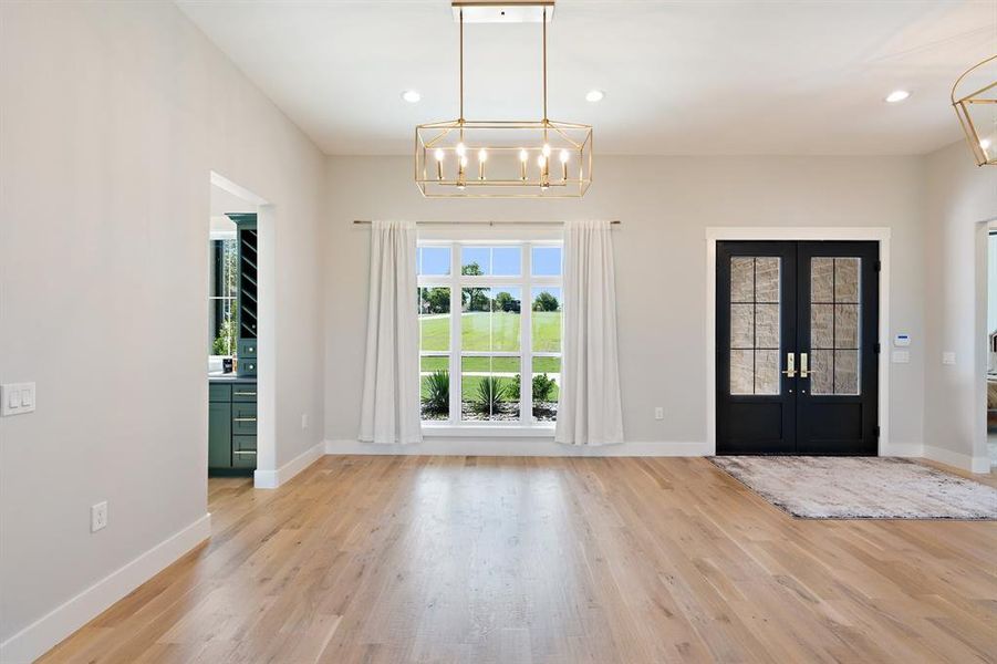 Entrance foyer featuring light hardwood / wood-style flooring, french doors, and a chandelier