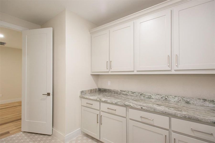 Kitchen with light stone counters, light wood-type flooring, and white cabinetry