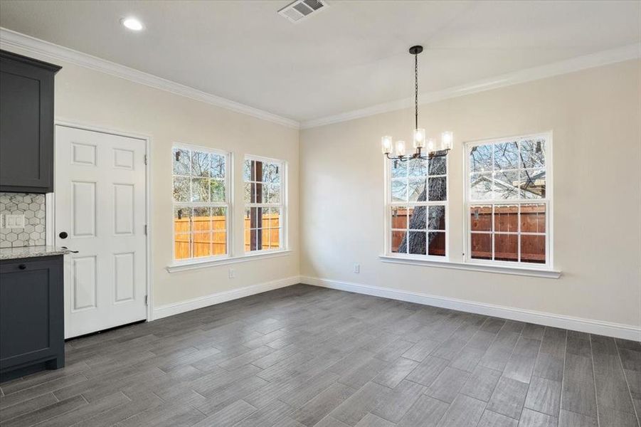 Unfurnished dining area featuring an inviting chandelier, hardwood / wood-style floors, and crown molding