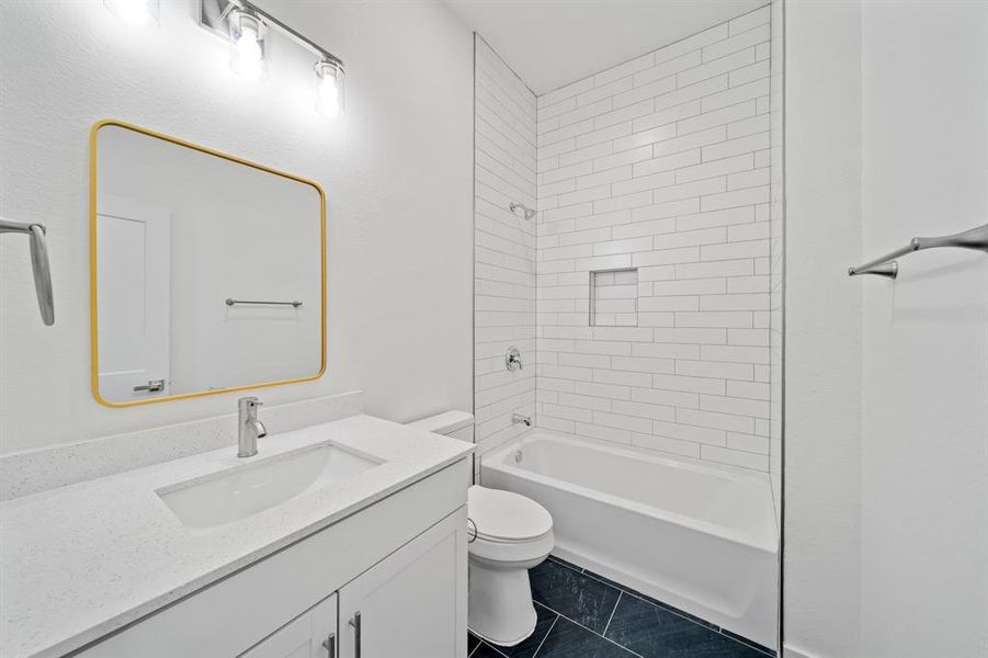 Full bathroom with tile patterned flooring, tiled shower / bath combo, toilet, and vanity