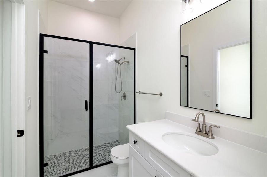 Bathroom with a shower with door, oversized vanity, and toilet