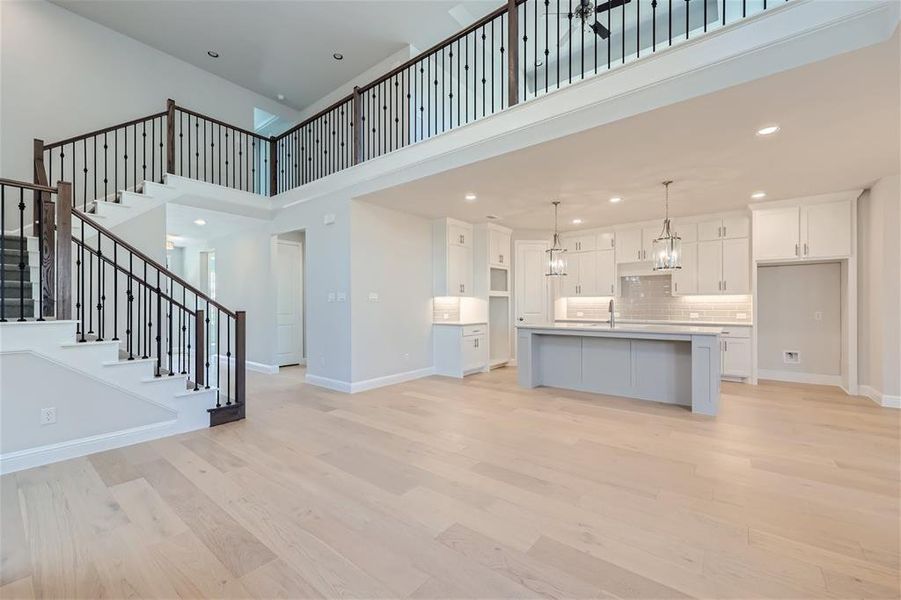 Kitchen with pendant lighting, light hardwood / wood-style flooring, a center island with sink, and white cabinetry