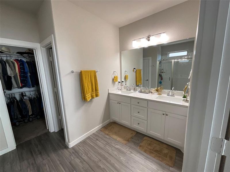 Bathroom with vanity, a shower with shower door, and hardwood / wood-style flooring