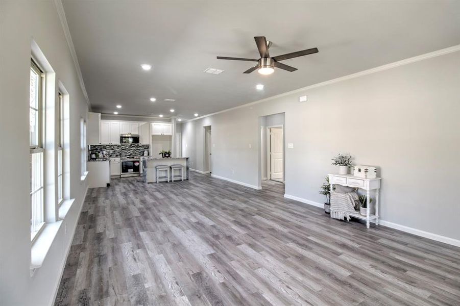 Unfurnished living room with a wealth of natural light, crown molding, and light hardwood / wood-style floors