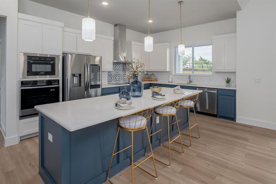 Kitchen with appliances with stainless steel finishes, white cabinetry, wall chimney exhaust hood, a breakfast bar area, and a kitchen island