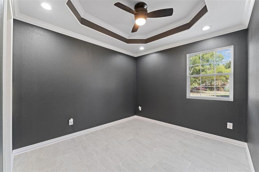 Spare room with crown molding, a raised ceiling, and ceiling fan