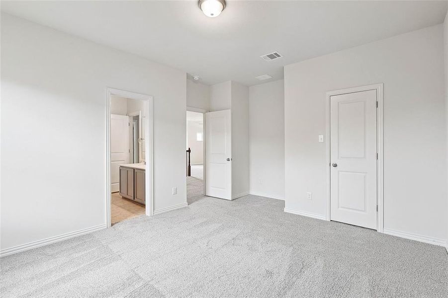 Unfurnished bedroom featuring light colored carpet, connected bathroom, and a closet