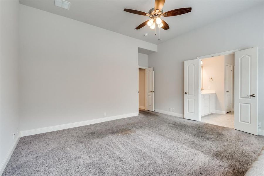 Unfurnished bedroom with light carpet, ceiling fan, and ensuite bathroom