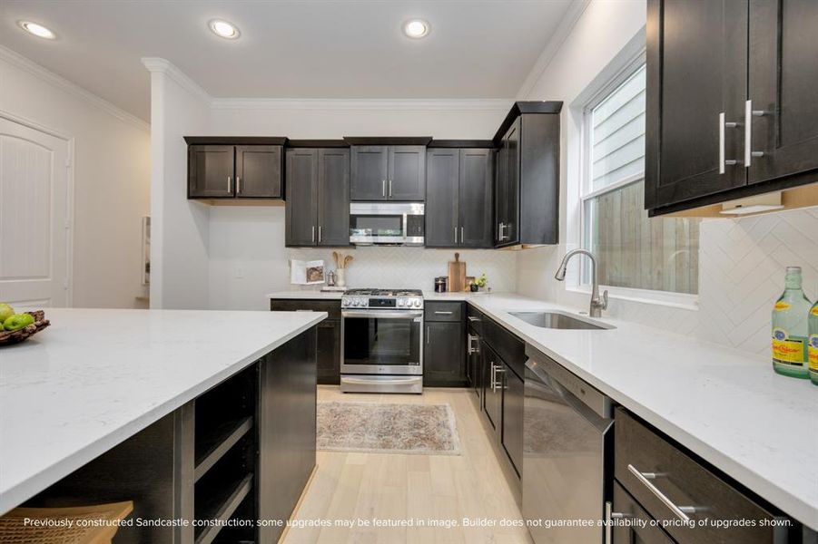 Unleash your culinary brilliance with a five-burner natural gas range, expansive undermount stainless steel sink with a modern gooseneck faucet, framed by ample storage within the island’s embrace.