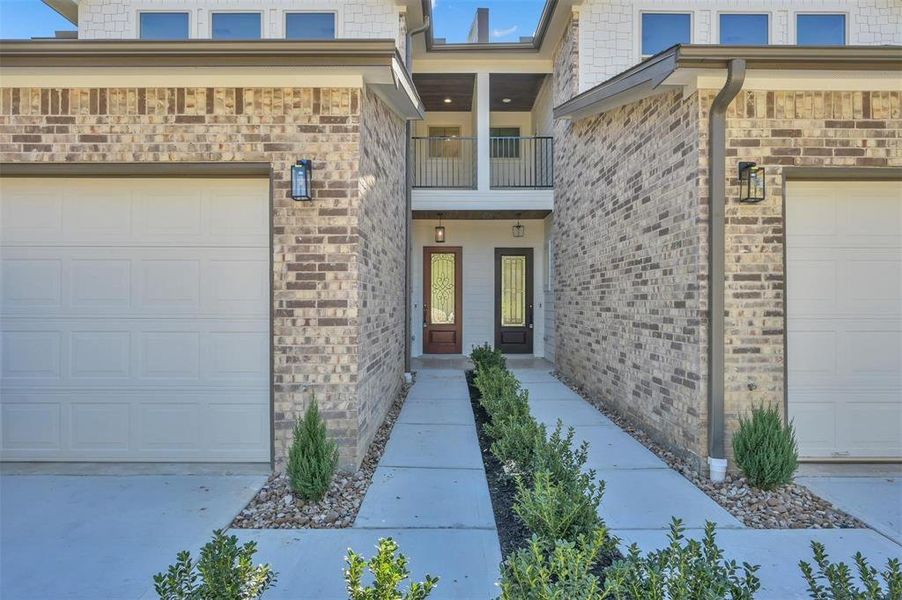 Nice landscaping welcomes you to the front door with overhead balcony.