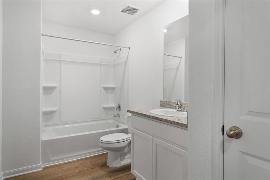 Secondary bathroom includes granite counters, designer white cabinetry and luxury vinyl plank flooring.