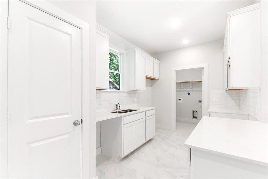 White cabinets, quartz countertops, subway tile backsplash and window at the kitchen sink.