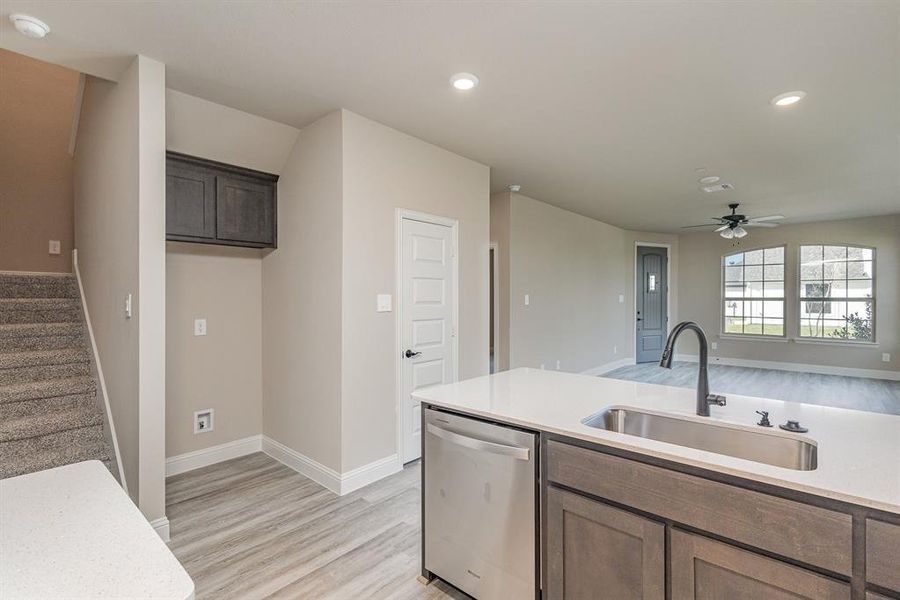 Kitchen featuring light hardwood / wood-style floors, stainless steel dishwasher, sink, and ceiling fan