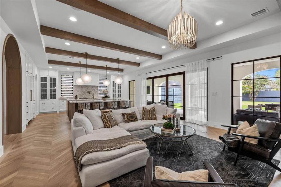 Living room featuring light parquet flooring, a chandelier, and beam ceiling