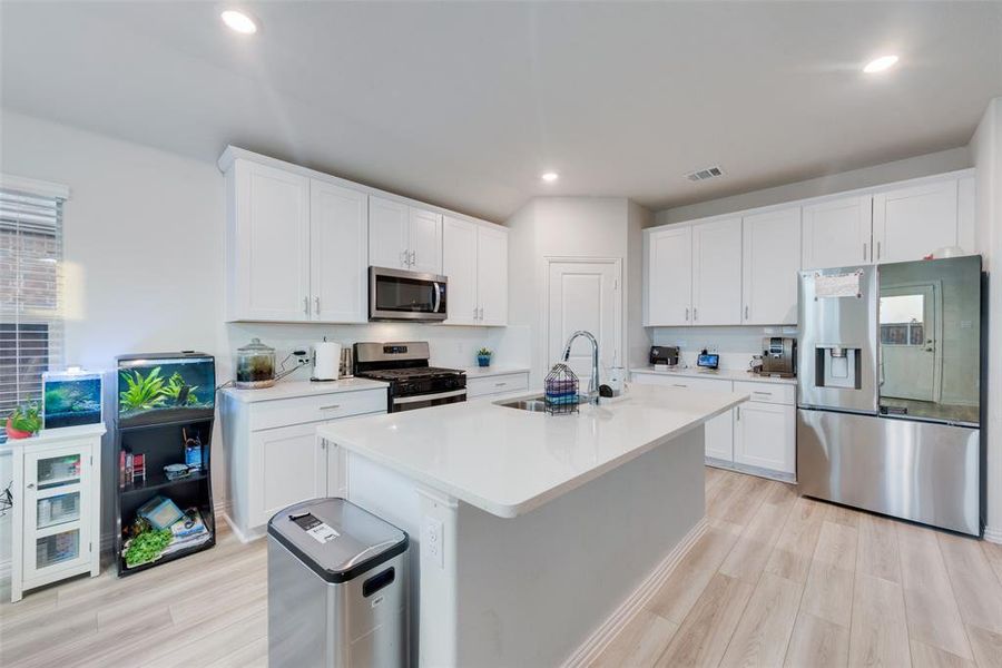 Kitchen featuring a center island with sink, white cabinetry, appliances with stainless steel finishes, and sink