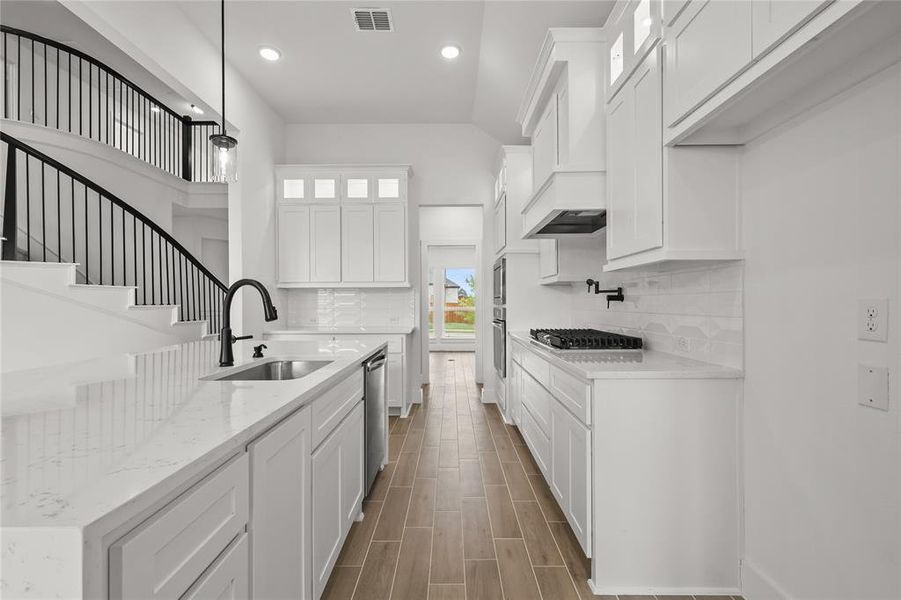 Kitchen with dishwasher, sink, gas stovetop, pendant lighting, and white cabinets