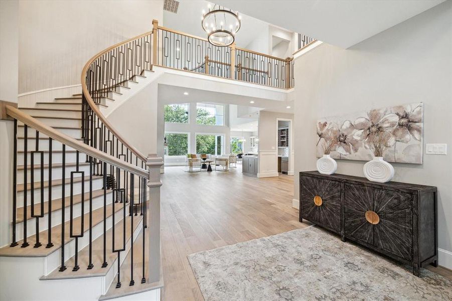 This is a breath taking home as you enter this spacious, open-concept interior featuring a sweeping staircase with modern metal balusters, high ceilings and abundant natural light. The view from the foyer shows a well-appointed living area and hints at a gourmet kitchen beyond.