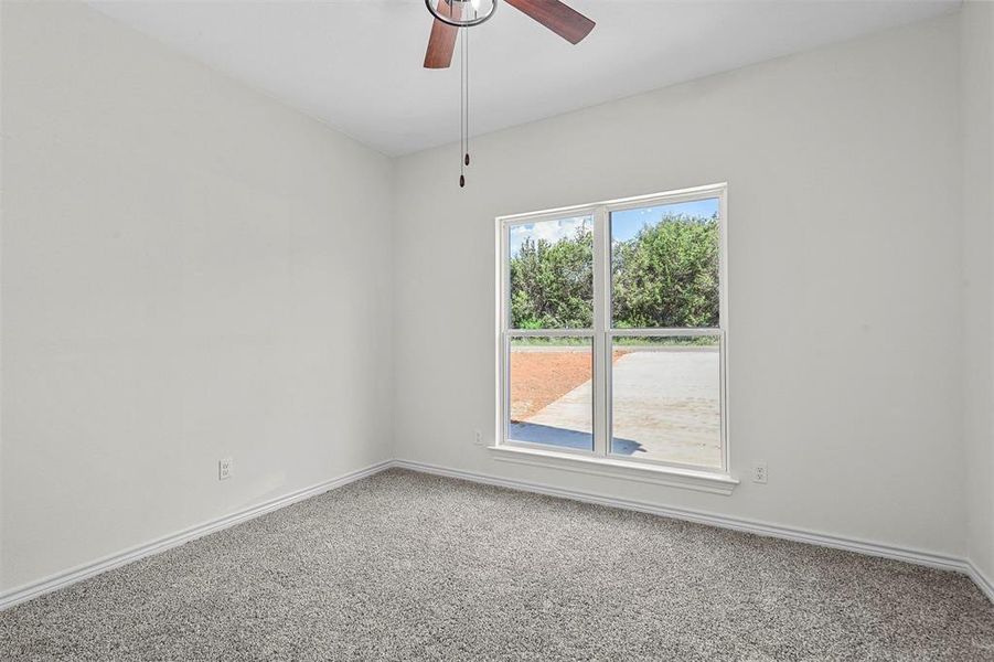 Carpeted empty room with ceiling fan and a wealth of natural light