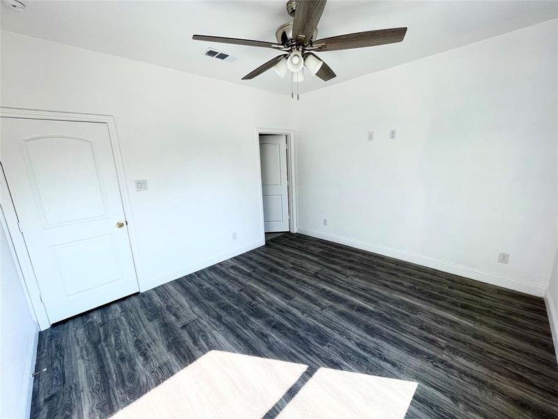 Empty room featuring ceiling fan and dark hardwood / wood-style flooring