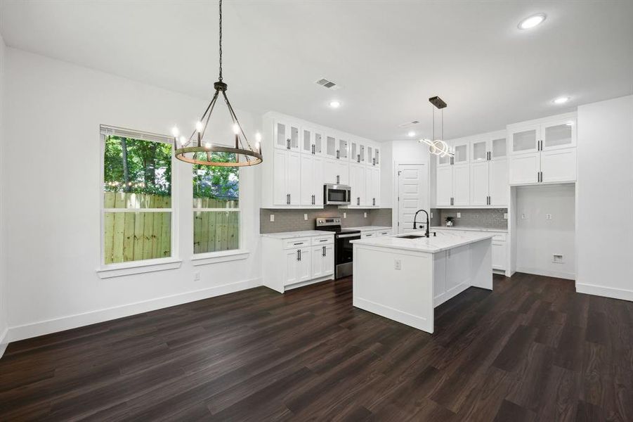 Kitchen with stainless steel appliances, dark wood-type flooring, and white cabinetry