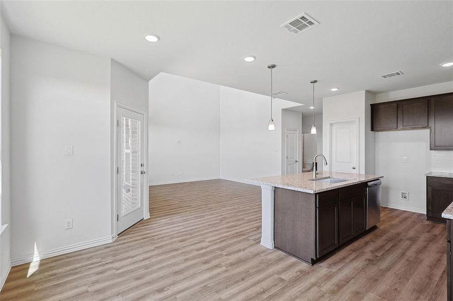 Kitchen featuring sink, dishwasher, an island with sink, and light wood-type flooring