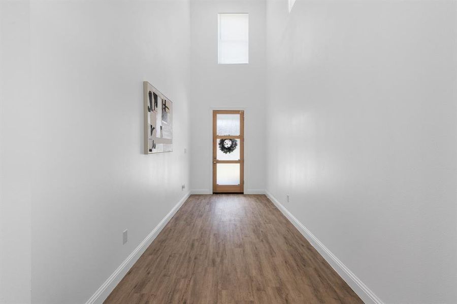 Doorway to outside featuring a towering ceiling and wood-type flooring