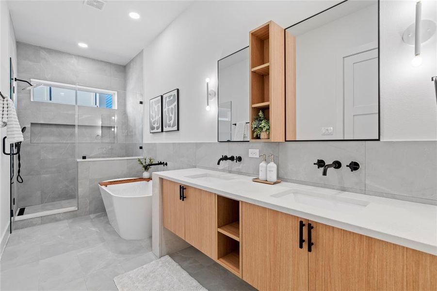 With its sleek double vanity, soothing gray tile, and thoughtfully placed lighting, this primary bathroom is designed for both beauty and convenience. The soaking tub and large shower offer a luxurious experience, perfect for relaxing after a long day.