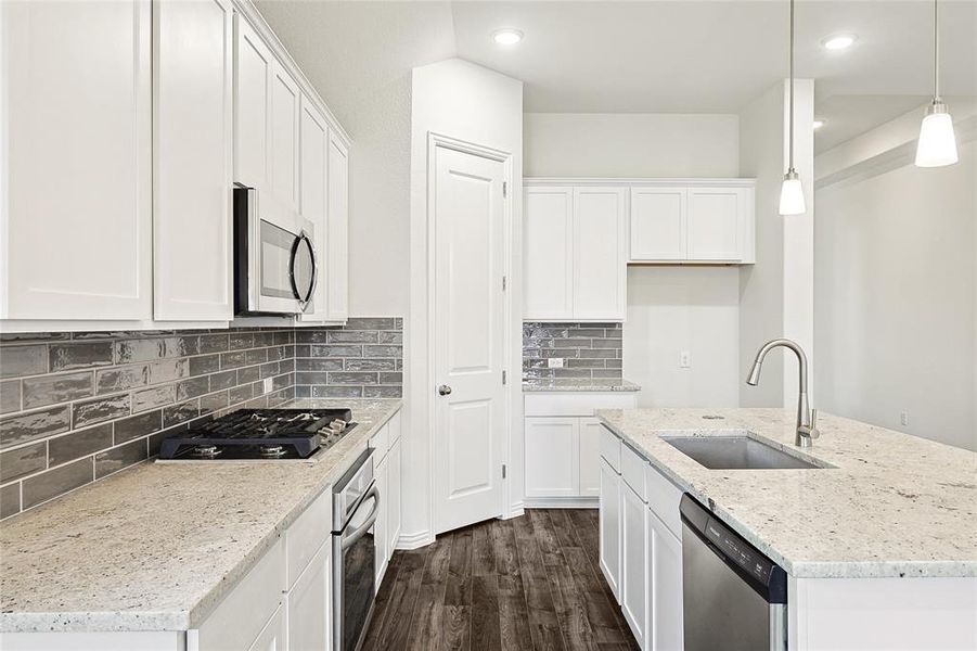 Kitchen featuring hanging light fixtures, stainless steel appliances, sink, dark hardwood / wood-style floors, and white cabinets